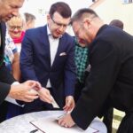 Wicestarosta Eligiusz Mich, prezydent Ostrowca Świętokrzyskiego Jarosław Górczyński i ks. Adam Gucwa wypełniają kapsułę czasu / Emilia Sitarska / Radio Kielce