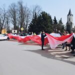 Skalbmierz. Mieszkańcy pozują do zdjęcia z prawie 30-metrową flagą / Karolina Kula