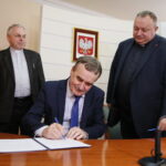 Urząd Stanu Cywilnego. Podpisanie porozumienia o współpracy dotyczącej organizowania pomocy materialnej dla ofiar wojny w Syrii oraz propagowania idei pokoju w świecie i unikania przemocy. Na zdjęciu: ks. Stanisław Słowik - dyrektor Caritas Diecezji Kieleckiej, Wojciech Lubawski - prezydent Kielc i ks. profesor Waldemar Cisło. Umowę podpisuje prezydent Kielc / Marzena Mąkosa / Radio Kielce