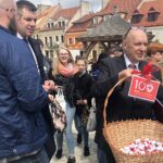 100 lat Polskiego Czerwonego krzyża. Happening w Sandomierzu. Prezes zarządu rejonowego PCK Z. Majewski częstuje uczestników happeningu krówkami / Grażyna-Szlęzak-Wójcik / Radio Kielce