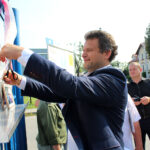 Kazimierza Wielka. Odsłonięcie tablicy „Solidarności” na bramie byłej Cukrowni Łubna. Na zdjęciu: wstęgę przecina Hubert Przybyszewki - regionalista, księgarz / Marta Gajda / Radio Kielce