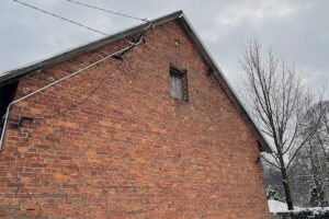 Dyszów. Dom, którego jedna ze ścian zbudowana została z cerkiewnych cegieł. Ciekawostką jest wmurowana w szczycie ściany twarz Jezusa Chrystusa. Monument również pochodzi z koneckiej cerkwi / Magdalena Galas-Klusek / Radio Kielce