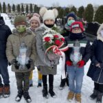 31.01.2021. Bilcza. Cmentarz parafialny. Dzieci z klasy III składają kwiaty i zapalają znicze pod tablicą poświęconą ks. Piotrowi Ściegiennemu / Kamil Król / Radio Kielce