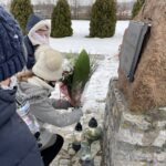 31.01.2021. Bilcza. Cmentarz parafialny. Dzieci z klasy III składają kwiaty i zapalają znicze pod tablicą poświęconą ks. Piotrowi Ściegiennemu / Kamil Król / Radio Kielce