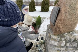 31.01.2021. Bilcza. Cmentarz parafialny. Dzieci z klasy III składają kwiaty i zapalają znicze pod tablicą poświęconą ks. Piotrowi Ściegiennemu / Kamil Król / Radio Kielce