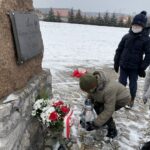 31.01.2021. Bilcza. Cmentarz parafialny. Dzieci z klasy III składają kwiaty i zapalają znicze pod tablicą poświęconą ks. Piotrowi Ściegiennemu / Kamil Król / Radio Kielce