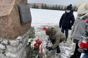 31.01.2021. Bilcza. Cmentarz parafialny. Dzieci z klasy III składają kwiaty i zapalają znicze pod tablicą poświęconą ks. Piotrowi Ściegiennemu / Kamil Król / Radio Kielce