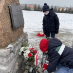 31.01.2021. Bilcza. Cmentarz parafialny. Dzieci z klasy III składają kwiaty i zapalają znicze pod tablicą poświęconą ks. Piotrowi Ściegiennemu / Kamil Król / Radio Kielce