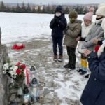 31.01.2021. Bilcza. Cmentarz parafialny. Dzieci z klasy III składają kwiaty i zapalają znicze pod tablicą poświęconą ks. Piotrowi Ściegiennemu / Kamil Król / Radio Kielce