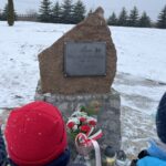 31.01.2021. Bilcza. Cmentarz parafialny. Dzieci z klasy III składają kwiaty i zapalają znicze pod tablicą poświęconą ks. Piotrowi Ściegiennemu / Kamil Król / Radio Kielce