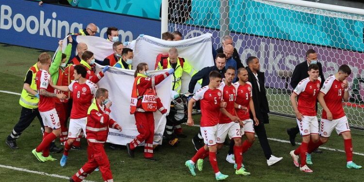 12.06.2021. Kopenhaga. Piłkarze Danii eskortują swojego kolegę z drużyny, Christiana Eriksena, po otrzymaniu pomocy medycznej podczas meczu rundy eliminacyjnej grupy B pomiędzy Danią i Finlandią UEFA EURO 2020 / PAP/EPA/Wolfgang Rattay / POOL