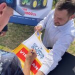 16.06.2021. Orłowiny. Przekazanie Radosławowi Gumińskiemu -  zwycięzcy loterii Grupy Azoty nowoczesnego ciągnika. Na zdjęciu: Piotr Żyła podpisuje się na ciągniku i koszulce / Emilia Sitarska / Radio Kielce