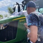 16.06.2021. Orłowiny. Przekazanie Radosławowi Gumińskiemu -  zwycięzcy loterii Grupy Azoty nowoczesnego ciągnika. Na zdjęciu: Piotr Żyła podpisuje się na ciągniku / Emilia Sitarska / Radio Kielce