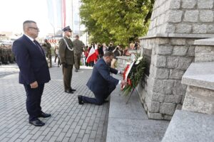 06.08.2021 Słomniki. 56. Marsz Szlakiem I Kompanii Kadrowej. Wieniec przed pomnikiem poległych i pomordowanych przez okupanta niemieckiego składa Jan Józef Kasprzyk - szef Urzędu do Spraw Kombatantów i Osób Represjonowanych w asyście Wojciecha Lasiaka - dyrektora gabinetu Jana Józefa Kasprzyka i płk Artura Frączka / Jarosław Kubalski / Radio Kielce