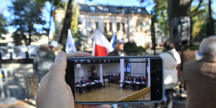 07.2021. Warszawa. Obrady TK oglądane na ekranie telefonu na tle demonstracji przed siedzibą Trybunału Konstytucyjnego w Warszawie / Radek Pietruszka / PAP