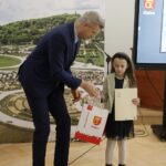 18.02.2022 Kielce. Wręczenie nagród i wyróżnień w konkursie plastycznym dla dzieci "Kielce- Moje Miasto w 2022 roku". Prezydent miasta Bogdan Wenta wręcza nagrodę Elenie Habie / Jarosław Kubalski / Radio Kielce