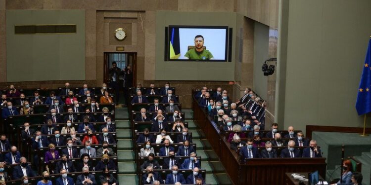 11.03.2022. Warszawa. Prezydent Ukrainy Wołodymyr Zełenski (na ekranie) przemawia podczas uroczystego zgromadzenia posłów i senatorów na sali plenarnej Sejmu w Warszawie. Zgromadzenie Narodowe odbyło się w przededniu 23. rocznicy wstąpienia Polski do NATO / PAP/Leszek Szymański