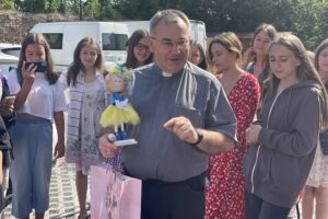 29.07.2022. Sandomierz. Koloniści z Kijowa w Sandomierzu. Na zdjęciu z lalką ks Bogusław Pitucha -dyrektor Caritas Diecezji Sandomierskiej. / Fot. Grażyna Szlęzak - Radio Kielce