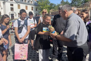 29.07.2022. Sandomierz. Koloniści z Kijowa w Sandomierzu. Na zdjęciu z lalką ks Bogusław Pitucha -dyrektor Caritas Diecezji Sandomierskiej. / Fot. Grażyna Szlęzak - Radio Kielce