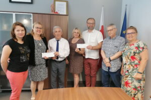 25.07.2022. Kazimierza Wielka. Przekazanie dwóch czeków dla samorządu Kazimierzy Wielkiej. Na zdjęciu (od lewej) Agnieszka Gaik - skarbnik UMiG Kazimierza Wielka, Bożena Serafin, Adam Bodzioch - burmistrz Kazimierza Wielka, Edyta Molo - dyrektor Miejsko - Gminnego Ośrodka Pomocy Społecznej w Kazimierzy Wielkiej, Łukasz Maderak - zastępca burmistrza, Andrzej Głogowiecki, dyrektor kazimierskiej „trójki”, Jolanta Nowak, prezes Kazimierskiego Stowarzyszenia „Amazonki”. / Fot. Marta Gajda-Kruk - Radio Kielce