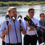 11.08.2022. Cigacice (woj. lubuskie), Sekretarz stanu w Ministerstwie Środowiska i Klimatu Jacek Ozdoba (w środku) i prezes Państwowego Gospodarstwa Wodnego Wody Polskie Przemysław Daca (drugi z prawej) na konferencji prasowej we wsi Cigacice. Spotkanie dotyczyło zanieczyszczenia Odry / Fot. Lech Muszyński - PAP