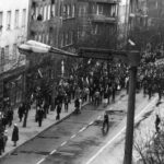 01.05.1982. Gdynia. Manifestacja idąca ulicą Świętojańską w Gdyni. W głębi widać tłum ludzi przechodzący przez kordon milicjantów stojący w poprzek drogi