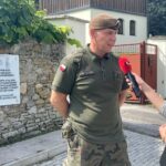 10.08.2023. Mokrsko Dolne. Delegacja 58. Marszu Szlakiem Pierwszej Kompanii Kadrowej złożyła wieńce i zapaliła znicze przed pamiątkową tablicą wmurowaną w kościelny mur. Na zdjęciu: ppor Daniel Woś - oficer kierunkowy marszu i zastępca komendanta marszu / Fot. Krzysztof Bujnowicz - Radio Kielce