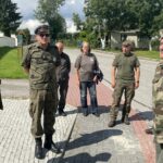 10.08.2023. Mokrsko Dolne. Delegacja 58. Marszu Szlakiem Pierwszej Kompanii Kadrowej złożyła wieńce i zapaliła znicze przed pamiątkową tablicą wmurowaną w kościelny mur / Fot. Krzysztof Bujnowicz - Radio Kielce