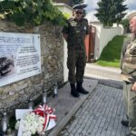 10.08.2023. Mokrsko Dolne. Delegacja 58. Marszu Szlakiem Pierwszej Kompanii Kadrowej złożyła wieńce i zapaliła znicze przed pamiątkową tablicą wmurowaną w kościelny mur / Fot. Krzysztof Bujnowicz - Radio Kielce