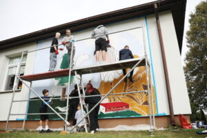 26.09.2024. Masłów. Uczniowie pod okiem artysty Mikołaja Korusa malują mural przedstawiający poetę Jana Kochanowskiego na budynku Szkoły Podstawowej w Brzezinkach / Fot. Wiktor Taszłow - Radio Kielce