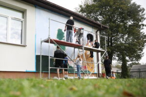 26.09.2024. Masłów. Uczniowie pod okiem artysty Mikołaja Korusa malują mural przedstawiający poetę Jana Kochanowskiego na budynku Szkoły Podstawowej w Brzezinkach / Fot. Wiktor Taszłow - Radio Kielce