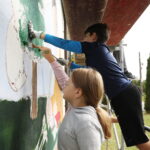 26.09.2024. Masłów. Uczniowie pod okiem artysty Mikołaja Korusa malują mural przedstawiający poetę Jana Kochanowskiego na budynku Szkoły Podstawowej w Brzezinkach / Fot. Wiktor Taszłow - Radio Kielce