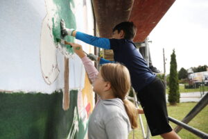 26.09.2024. Masłów. Uczniowie pod okiem artysty Mikołaja Korusa malują mural przedstawiający poetę Jana Kochanowskiego na budynku Szkoły Podstawowej w Brzezinkach / Fot. Wiktor Taszłow - Radio Kielce