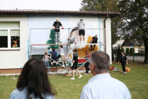 26.09.2024. Masłów. Uczniowie pod okiem artysty Mikołaja Korusa malują mural przedstawiający poetę Jana Kochanowskiego na budynku Szkoły Podstawowej w Brzezinkach / Fot. Wiktor Taszłow - Radio Kielce