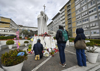 13.03.2025. Włochy. Rzym. Wierni modlą się przed pomnikiem Jana Pawła II przy wejściu do szpitala Gemelli, w którym nadal hospitalizowany jest papież Franciszek / Fot. PAP / EPA - Riccardo Antimiani