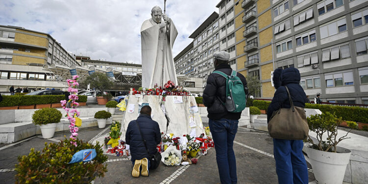 13.03.2025. Włochy. Rzym. Wierni modlą się przed pomnikiem Jana Pawła II przy wejściu do szpitala Gemelli, w którym nadal hospitalizowany jest papież Franciszek / Fot. PAP / EPA - Riccardo Antimiani